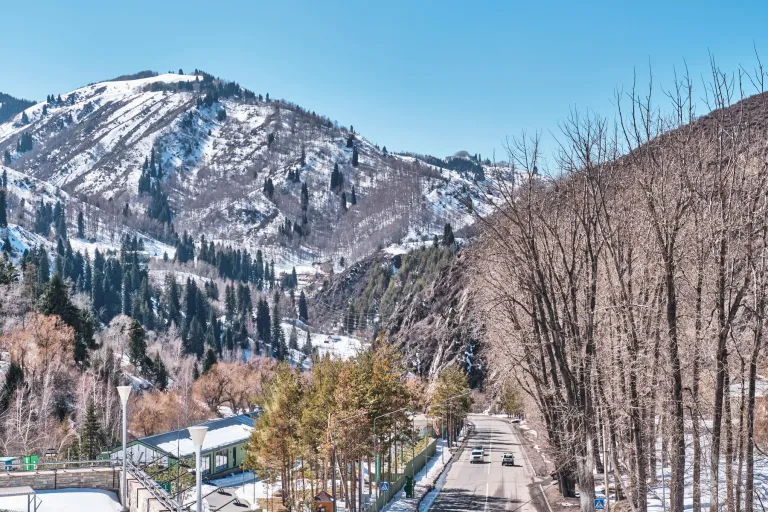 Snowy road and wooded slopes at Shymbulak ski resort