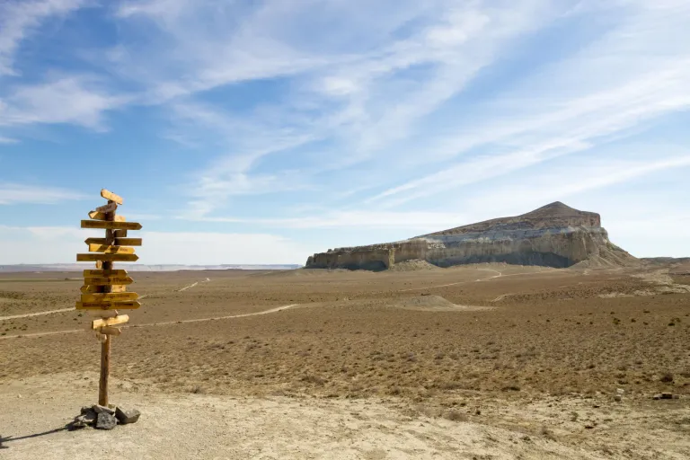 Direction sign beside the dry plain and cliffs of Airakty-Shomanai