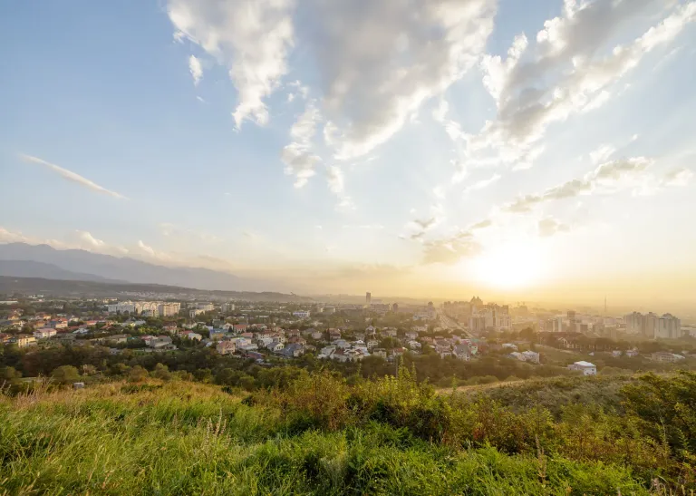 Sunset over Almaty viewed from a grassy hillside