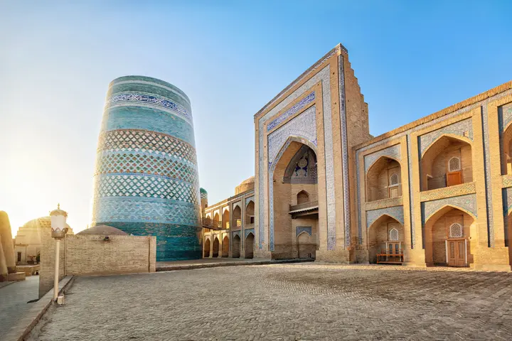Turquoise Kalta Minor Minaret beside a tiled madrasa facade in Khiva