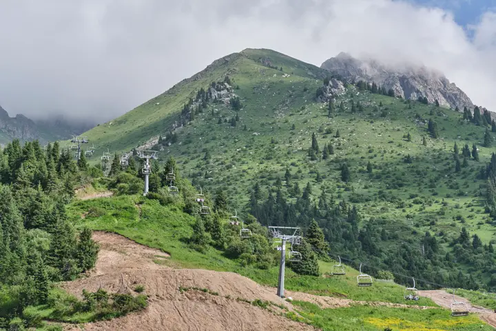 Chairlift towers on a green mountain slope beneath low cloud