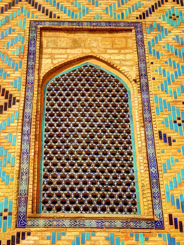 Turquoise and golden tilework around an arched window in Turkistan