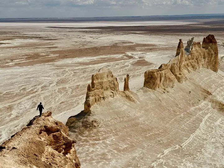 Visitor on a narrow rock ridge above the pale Mangystau desert