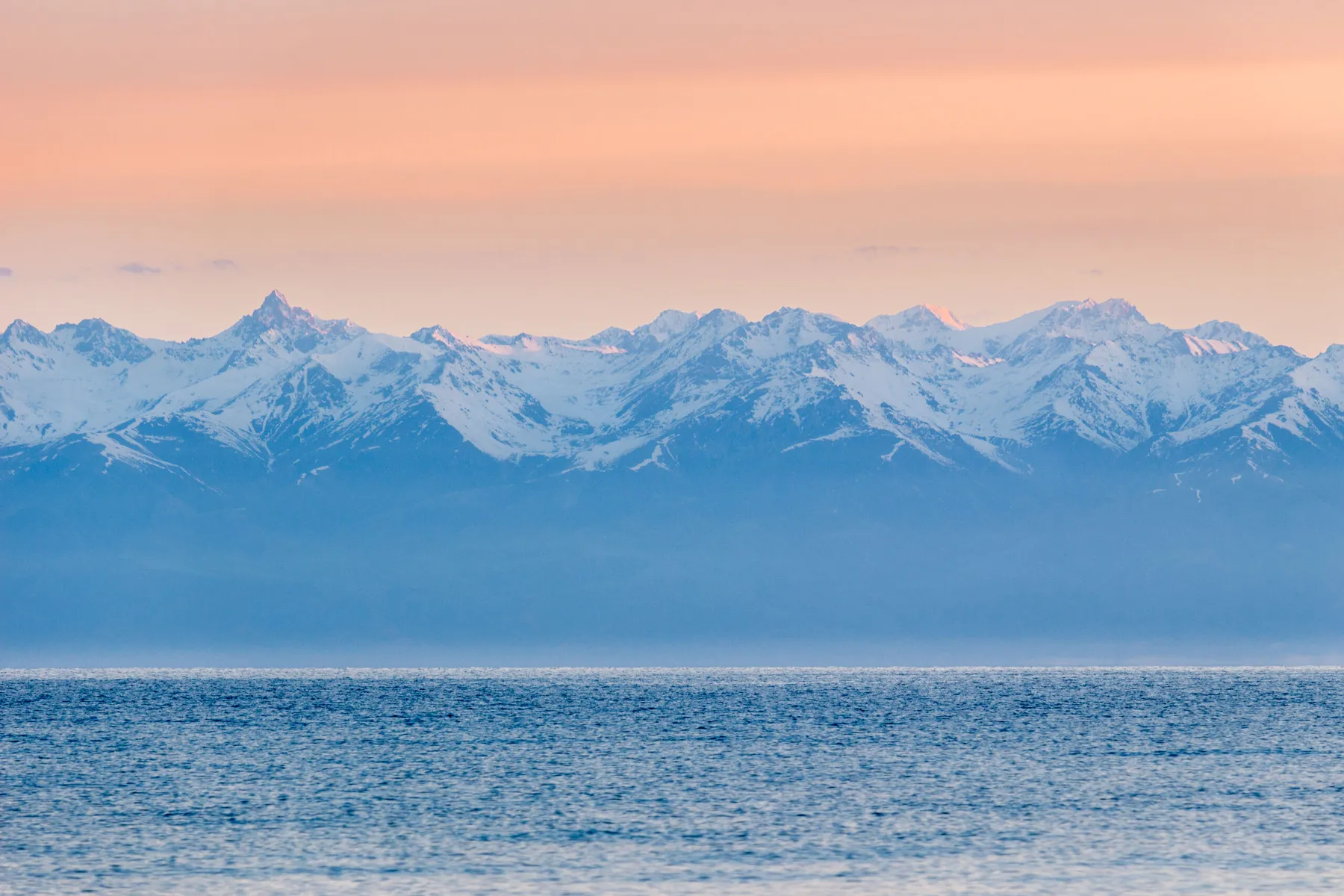 Snow-capped Tian Shan mountains beyond the blue waters of Issyk-Kul Lake